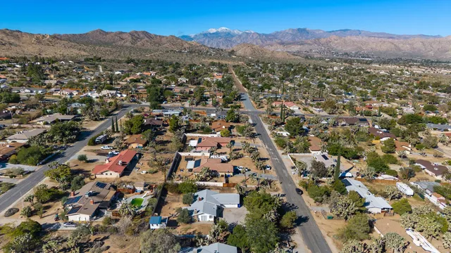 an aerial view of residential house with parking and mountain view in back