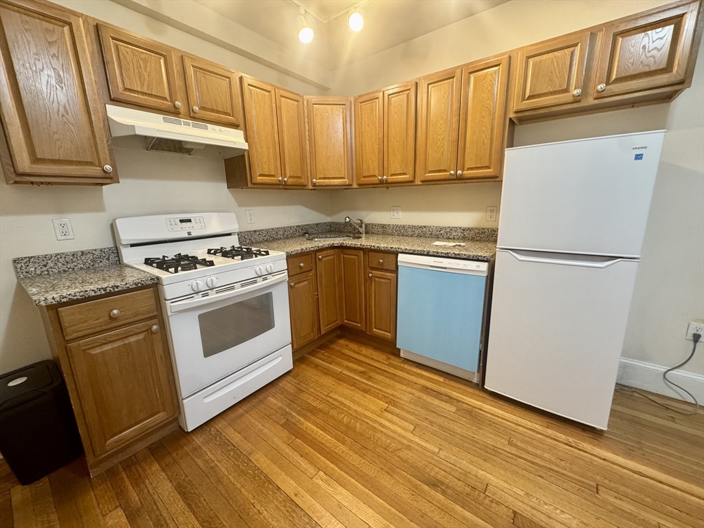 1615 Commonwealth Avenue, Unit 11 Boston, MA 02135 - Photo 1 of 9 a kitchen with granite countertop wooden cabinets stainless steel appliances and a sink