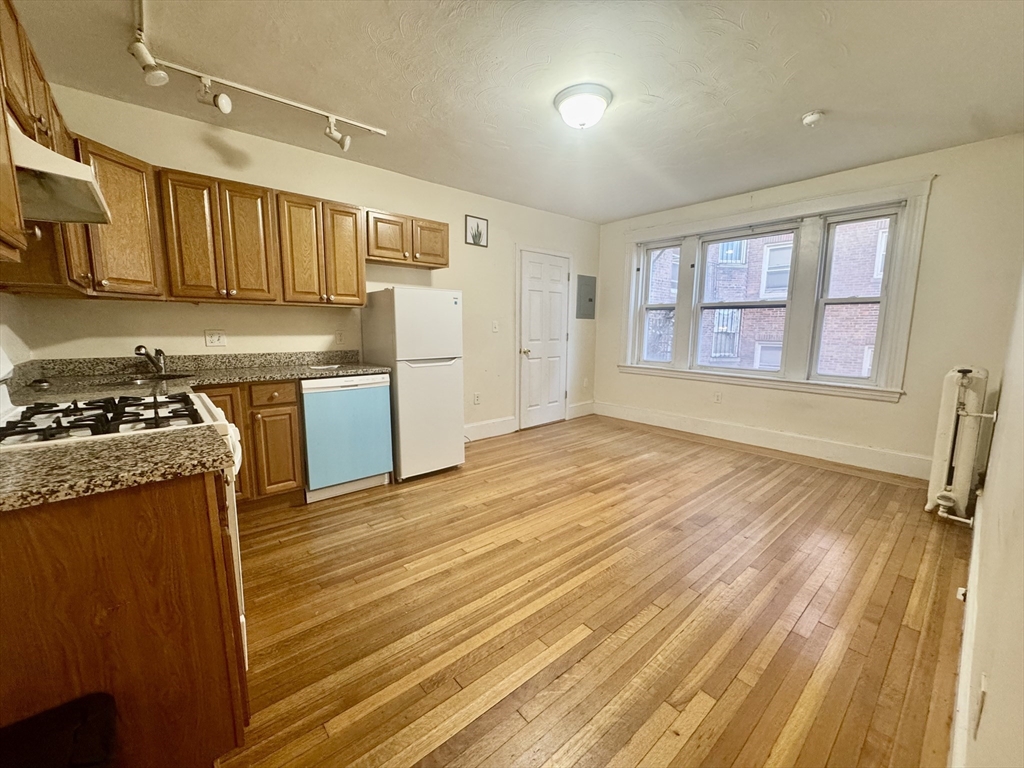 1615 Commonwealth Avenue, Unit 11 Boston, MA 02135 - Photo 2 of 9 a kitchen with stainless steel appliances granite countertop a sink and wooden cabinets