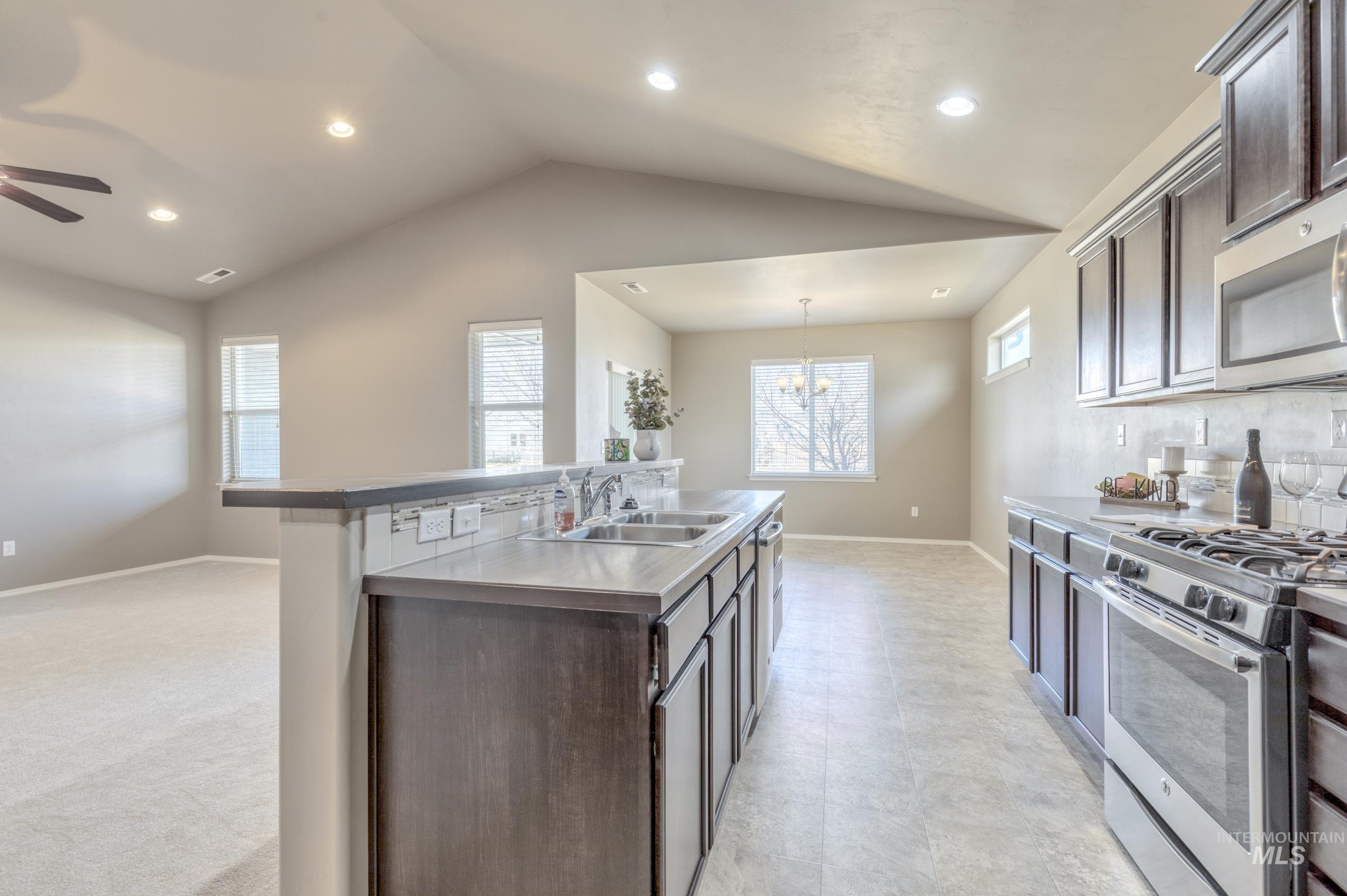 12734 Amber Sky Drive Caldwell, ID 83607 - Photo 8 of 28 Kitchen featuring dark wood finish cabinets, stainless steel appliances, a center island with sink, and ceiling fan