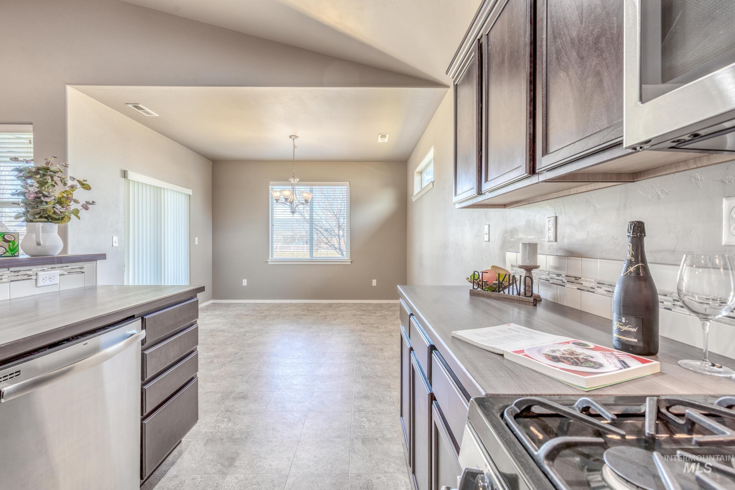 12734 Amber Sky Drive Caldwell, ID 83607 - Photo 9 of 28 Kitchen with stainless steel appliances, suspended lighting, light countertops, and dark wood finish cabinets