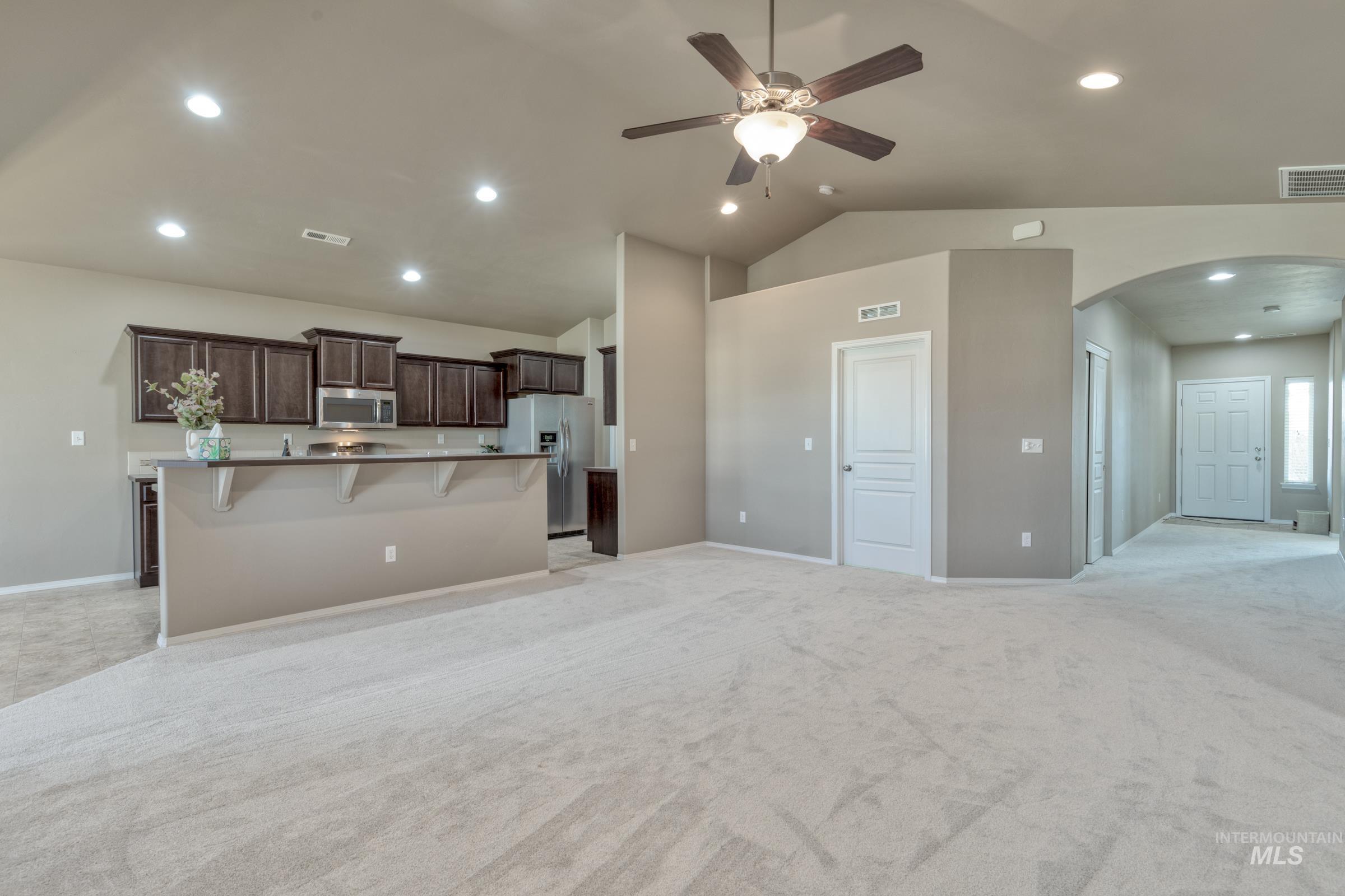 12734 Amber Sky Drive Caldwell, ID 83607 - Photo 26 of 28 Kitchen with open floor plan, a kitchen breakfast bar, arched walkways, ceiling fan, and dark wood finish cabinetry