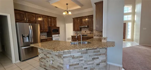 a kitchen with stainless steel appliances granite countertop a refrigerator a stove and a sink