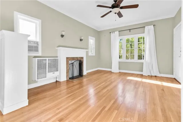 a view of an empty room with window and wooden floor