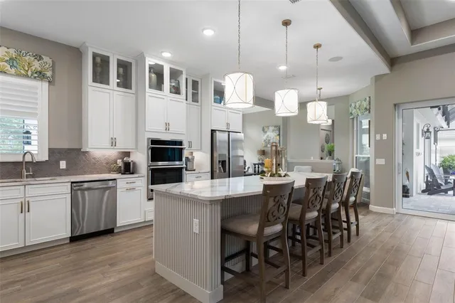 a dining hall with stainless steel appliances granite countertop a stove a sink a dining table and chairs with wooden floor