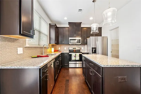 a kitchen with granite countertop a sink stove and refrigerator