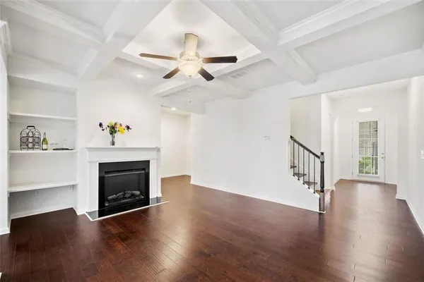 a view of a livingroom with wooden floor a fireplace a ceiling fan and a window