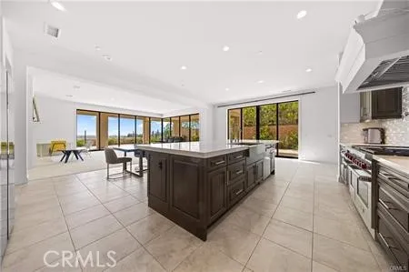 a large kitchen with stainless steel appliances granite countertop a large counter top a stove a chimney a sink and a large window