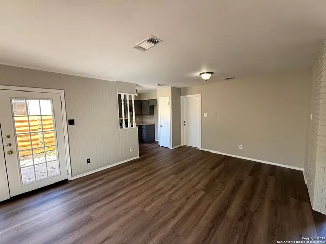 a view of an empty room with wooden floor and a window