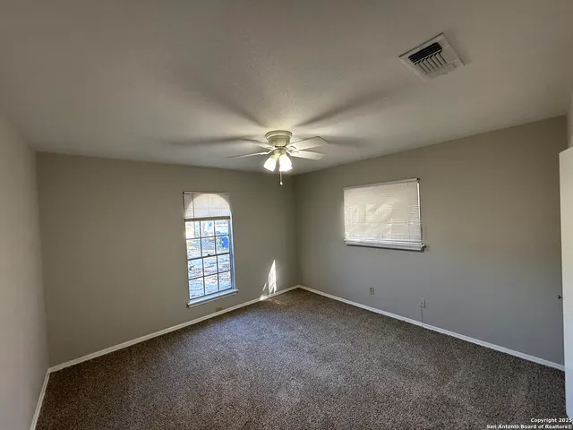 an empty room with windows and ceiling fan