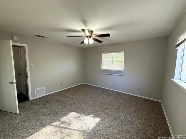 an empty room with windows and fan