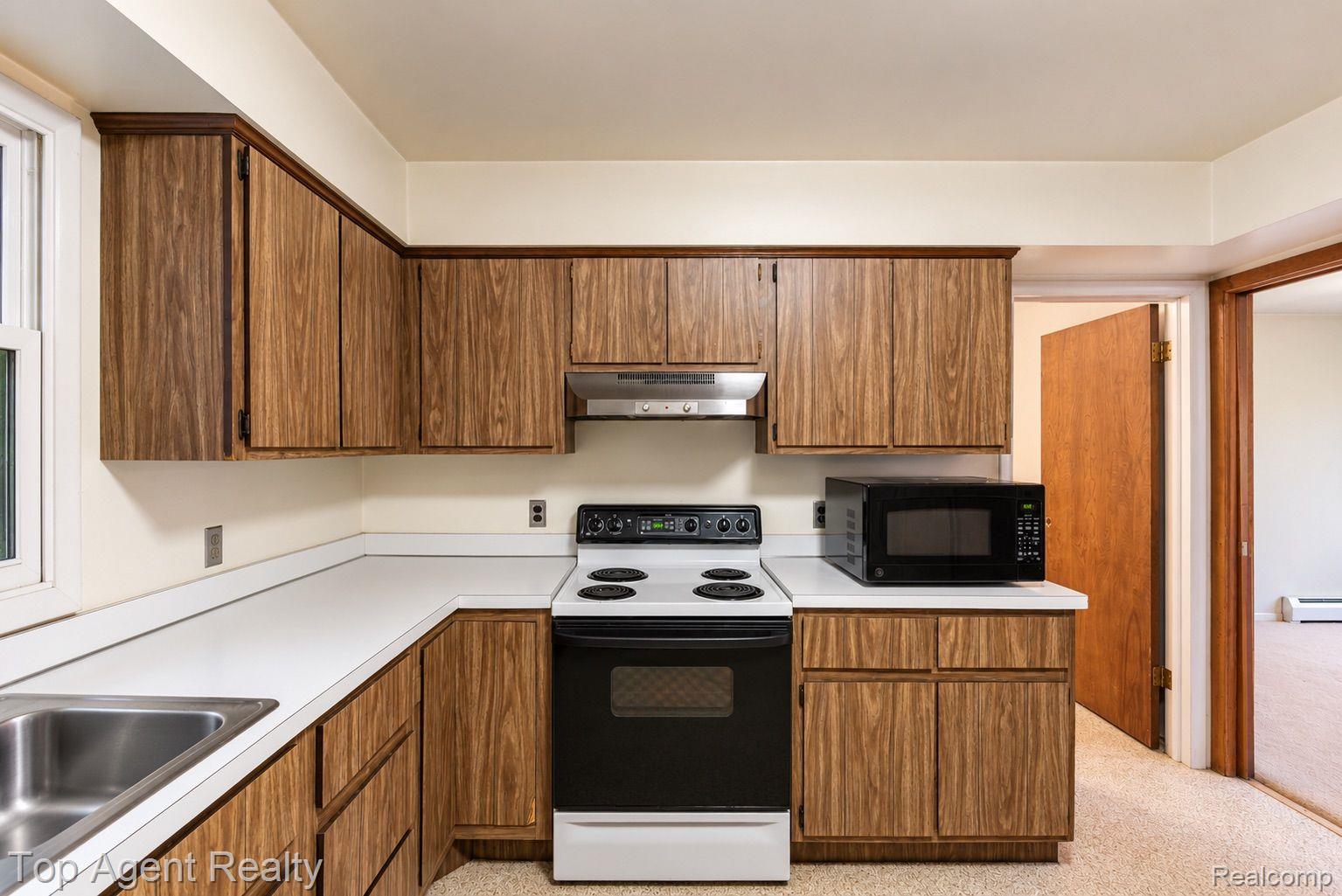 8269 Currie Road Northville, MI 48168 - Photo 15 of 80 Kitchen featuring wood-finish cabinetry, white countertops, stainless steel sink, and white appliances