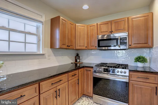a kitchen with stainless steel appliances granite countertop a sink a stove a microwave and cabinets