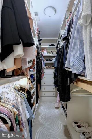 a view of walk in closet with clothes and shoes