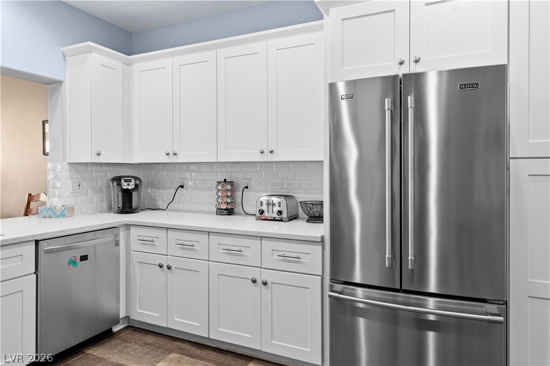 3350 Pheasant Canyon Way, Unit 1008 Laughlin, NV 89029 - Photo 15 of 80 Kitchen featuring appliances with stainless steel finishes, white cabinetry, dark wood-type flooring, and backsplash