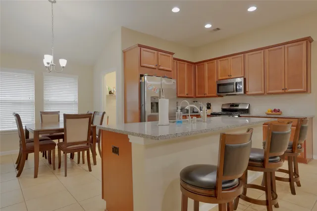 a kitchen with stainless steel appliances granite countertop a table chairs refrigerator and a sink