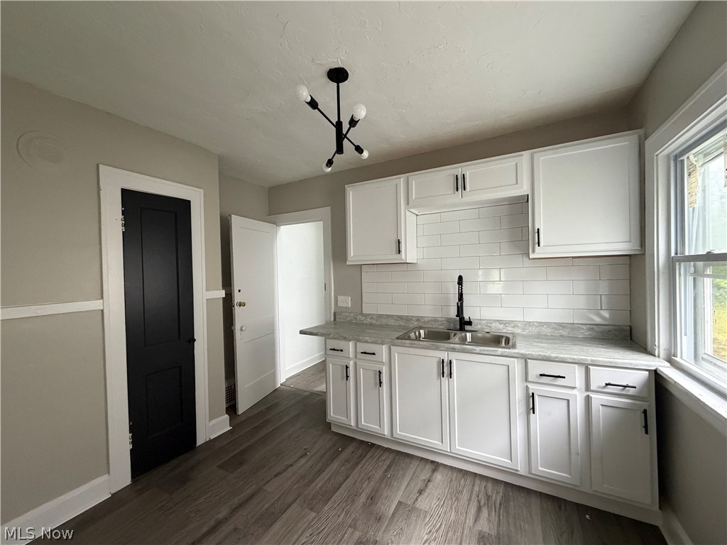 15317 Shiloh Road Cleveland, OH 44110 - Photo 11 of 29 Kitchen featuring white cabinetry with black hardware, a subway tile backsplash, and a double basin sink with a black faucet