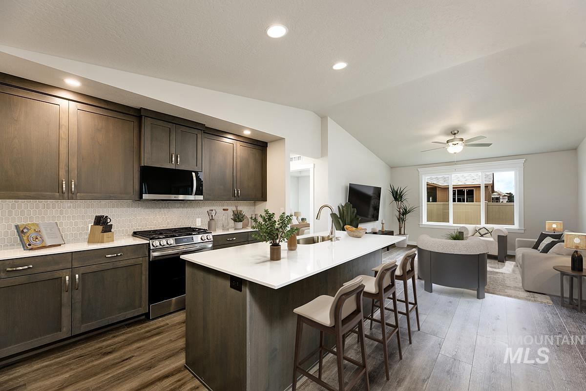 7080 South Gamely Avenue Meridian, ID 83642 - Photo 30 of 30 Kitchen featuring open floor plan, stainless steel appliances, dark wood finish cabinetry, a kitchen island with sink, and vaulted ceiling
