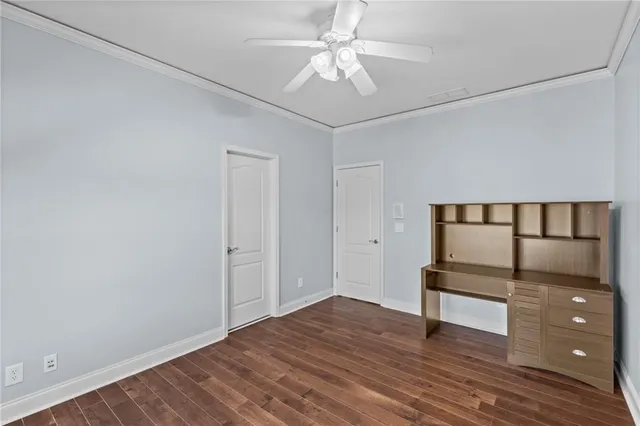 a view of an empty room with wooden floor and a ceiling fan