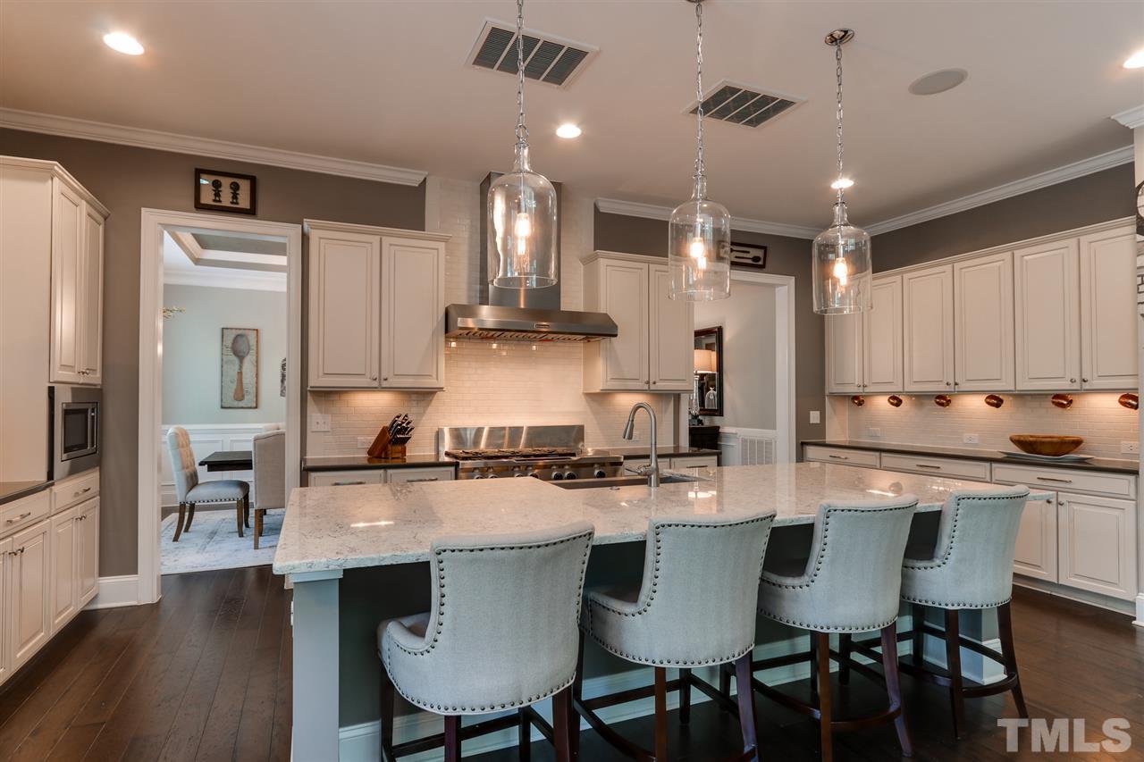 8105 Greys Landing Way Raleigh, NC 27615 - Photo 7 of 30 a kitchen with stainless steel appliances kitchen island granite countertop a dining table chairs and a refrigerator