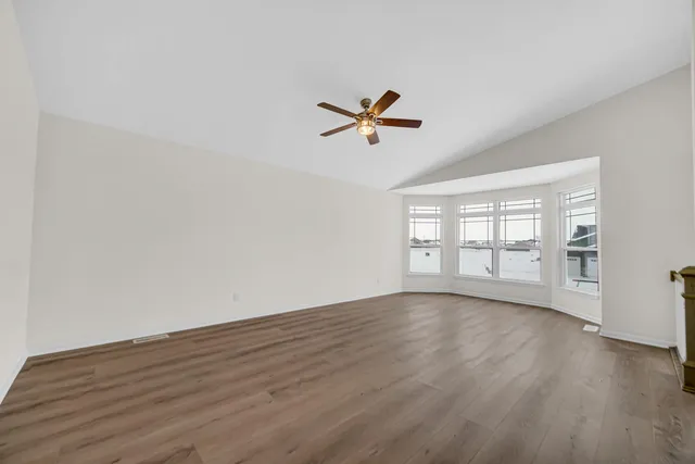 a view of empty room with wooden floor and fan
