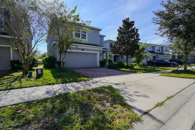 a front view of a house with a garden and tree