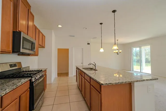 a kitchen with stainless steel appliances granite countertop a sink a stove and a wooden floor