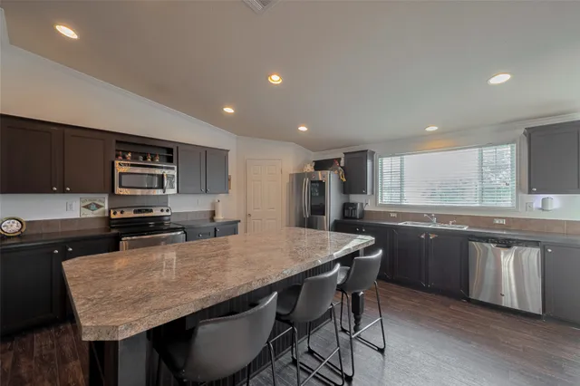 a kitchen with granite countertop kitchen island wooden cabinets and refrigerator