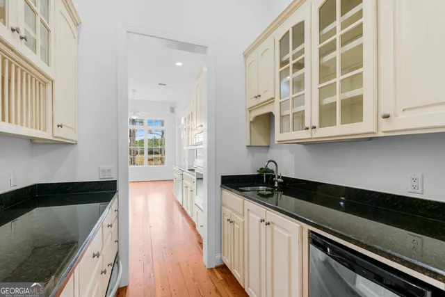 a kitchen with granite countertop wooden floors white cabinets and stainless steel appliances