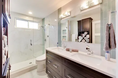 a bathroom with a double vanity sink toilet mirror and shower