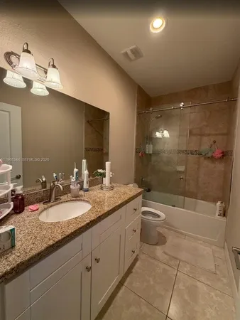 a bathroom with a granite countertop sink a toilet a mirror and shower