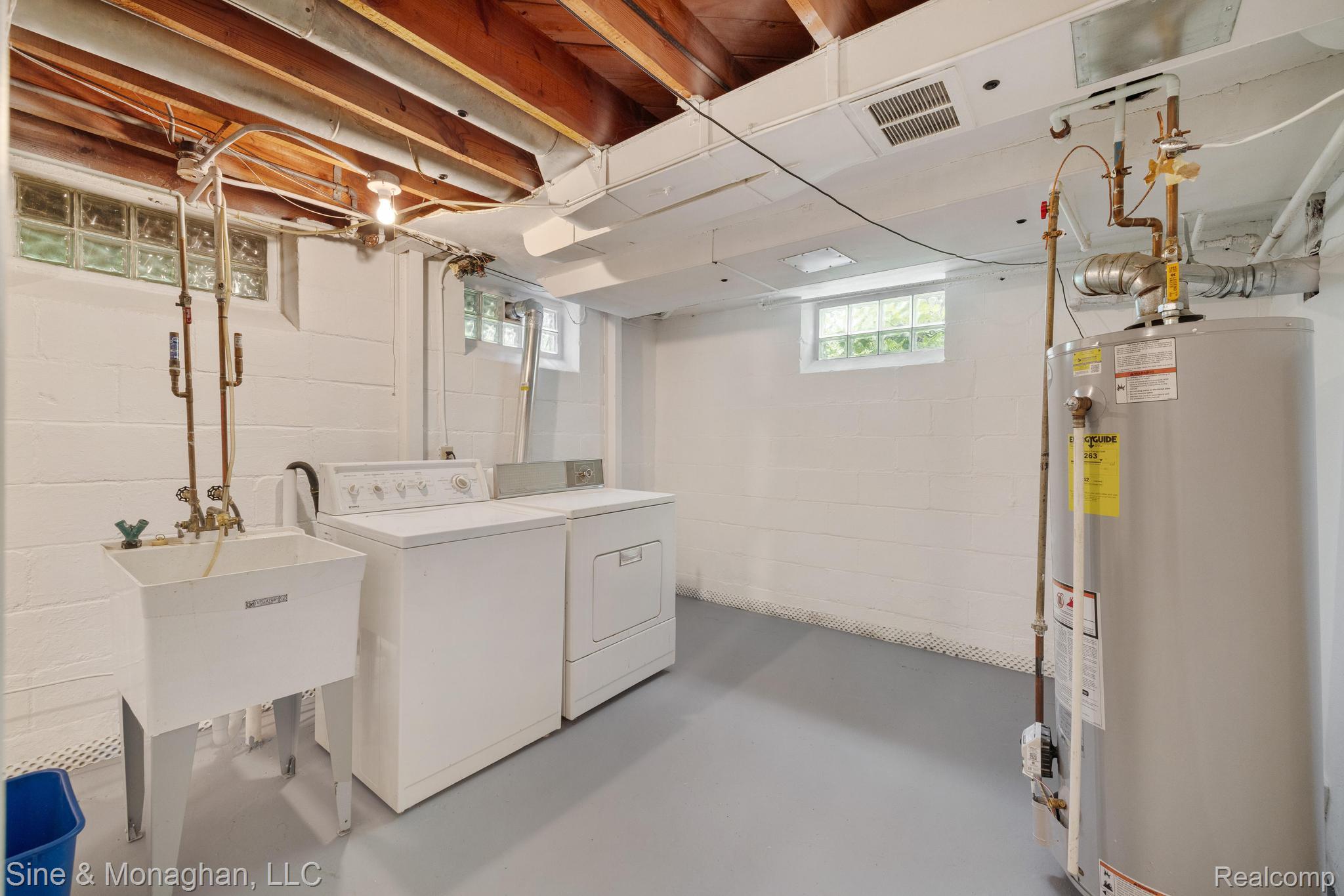 679 Neff Road Grosse Pointe, MI 48230 - Photo 37 of 78 Finished basement area featuring a utility sink, washer, dryer, water heater, and glass block windows