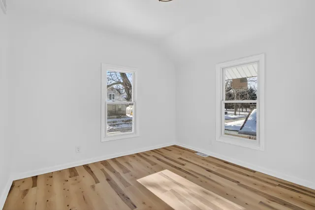 a view of a bedroom with wooden floor and window