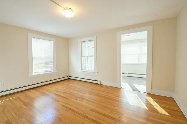 an empty room with wooden floor cabinet and windows