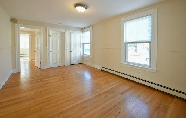 an empty room with wooden floor and windows