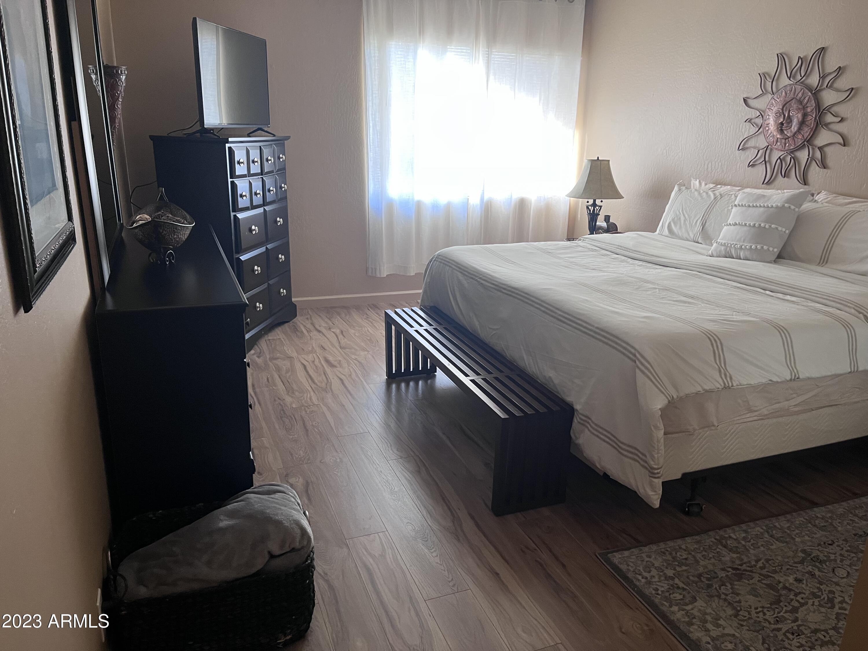 4600 North 68th Street, Unit 356 Scottsdale, AZ 85251 - Photo 11 of 16 a bedroom with a bed and dresser with wooden floor