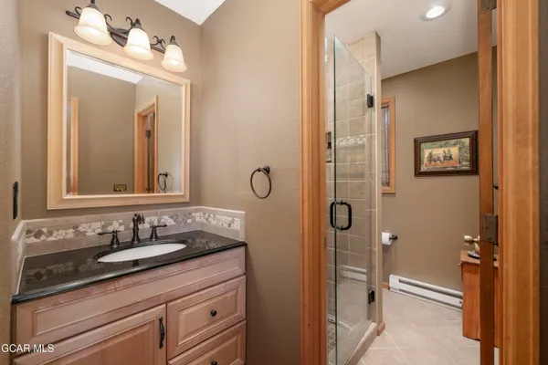 a bathroom with a granite countertop sink a mirror a vanity and a shower