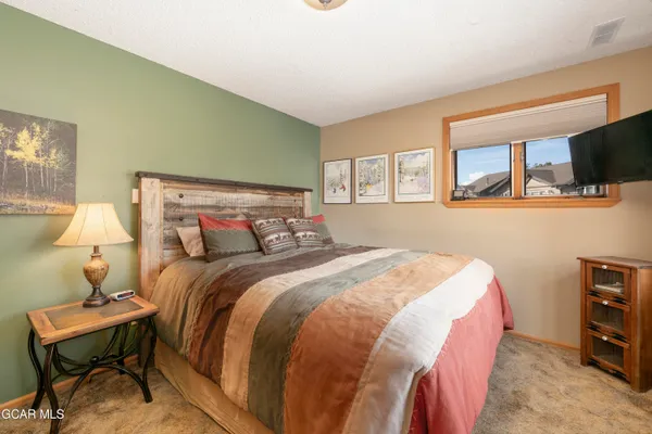 a bedroom with a bed a dresser and painting on the wall