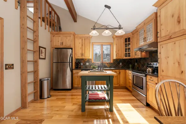 a kitchen with stainless steel appliances granite countertop a refrigerator a stove and a sink