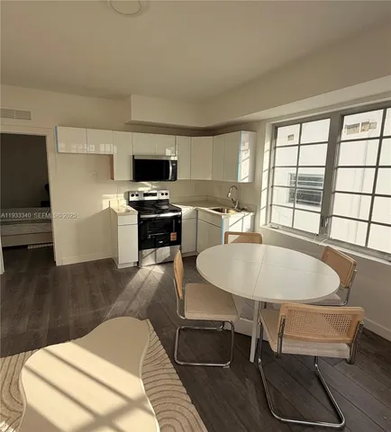 a living room with furniture a flat screen tv and kitchen view