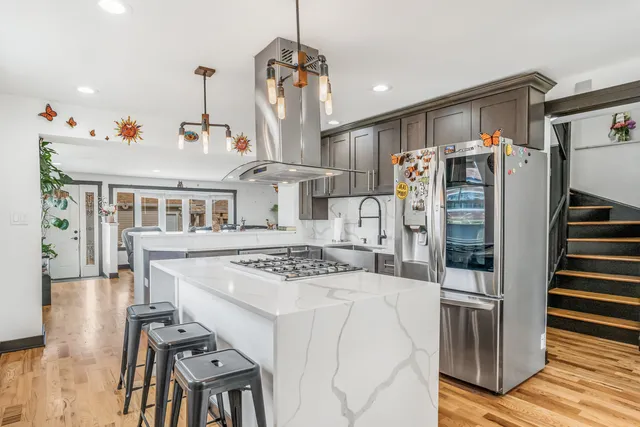 a kitchen with stainless steel appliances granite countertop a refrigerator a stove and a sink