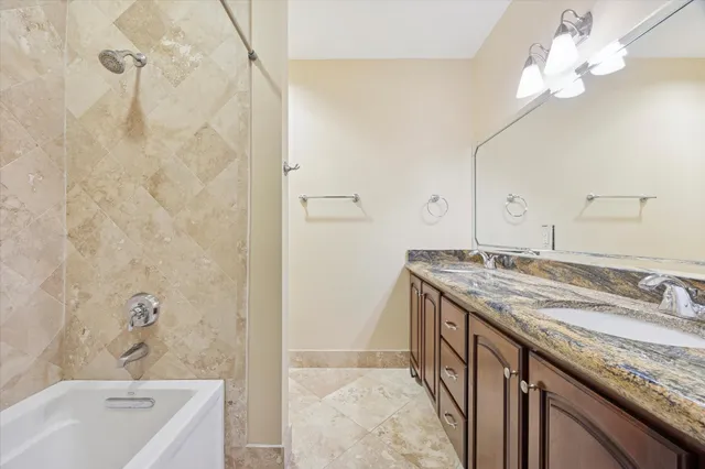 a bathroom with a granite countertop sink a large mirror and a bathtub
