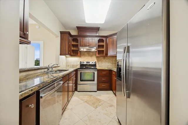 a kitchen with stainless steel appliances granite countertop a refrigerator and a stove