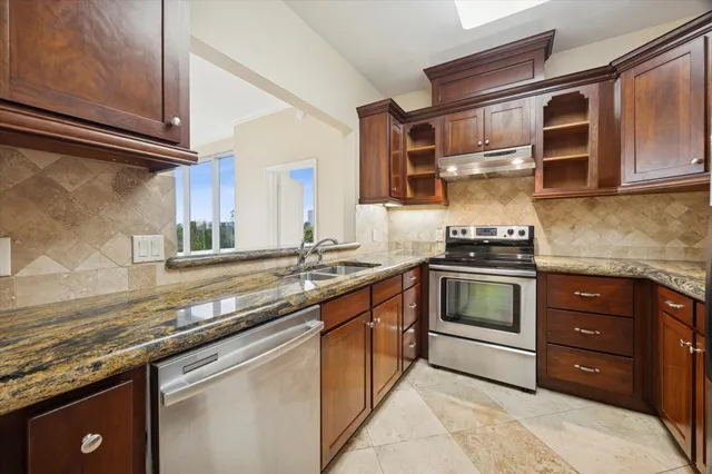 a kitchen with stainless steel appliances granite countertop a stove a sink and a microwave