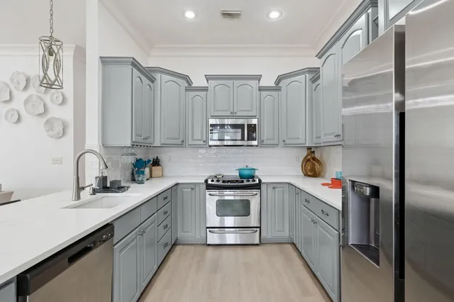 a kitchen with stainless steel appliances a table chairs microwave and refrigerator
