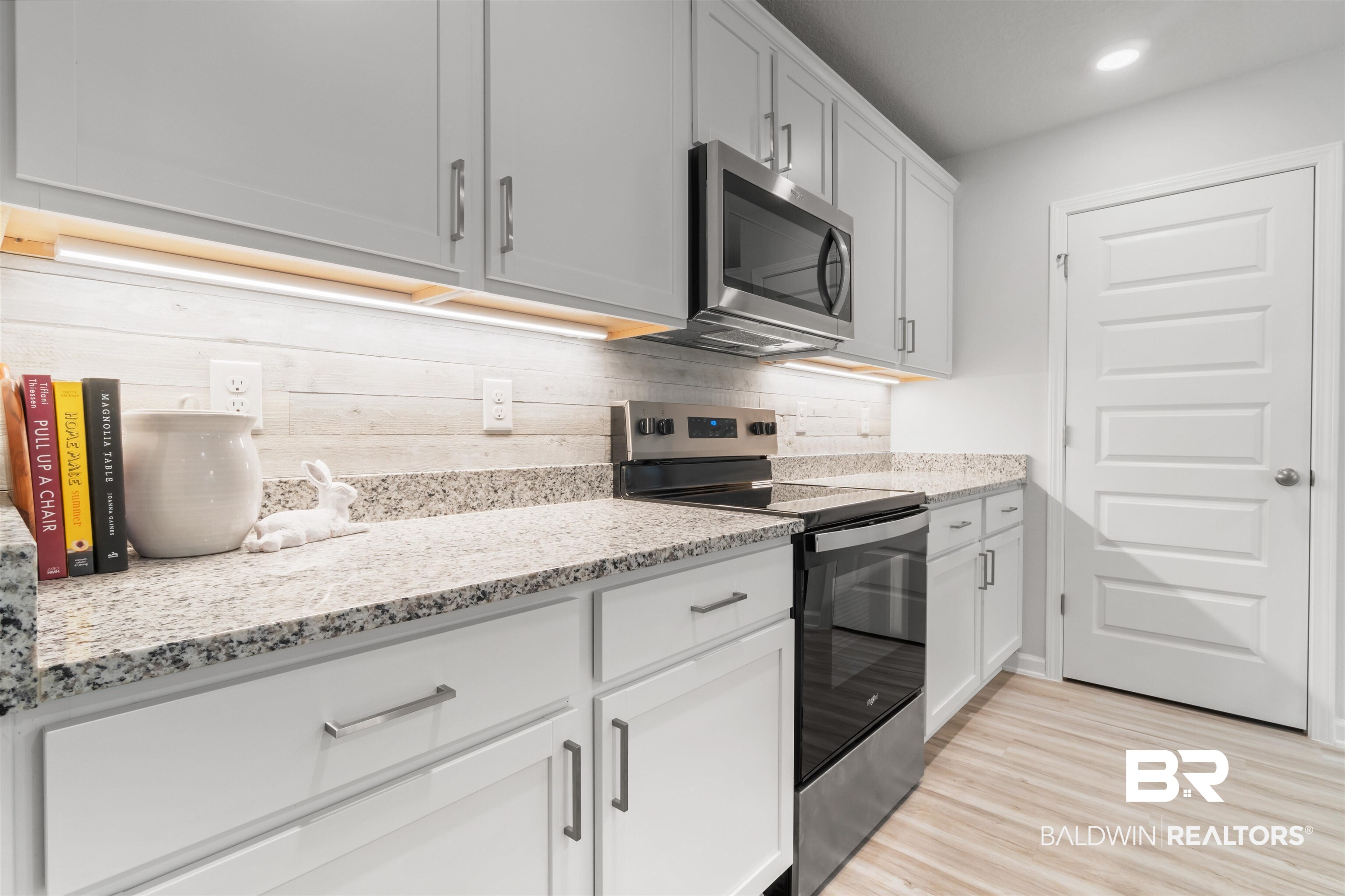 24472 Ringneck Loop Elberta, AL 36530 - Photo 11 of 46 Kitchen featuring light stone countertops, white cabinetry, appliances with stainless steel finishes, decorative backsplash, and light wood finished floors