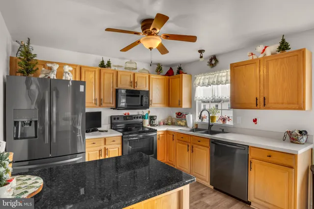 a kitchen with stainless steel appliances granite countertop a sink a stove cabinets counter space and a window