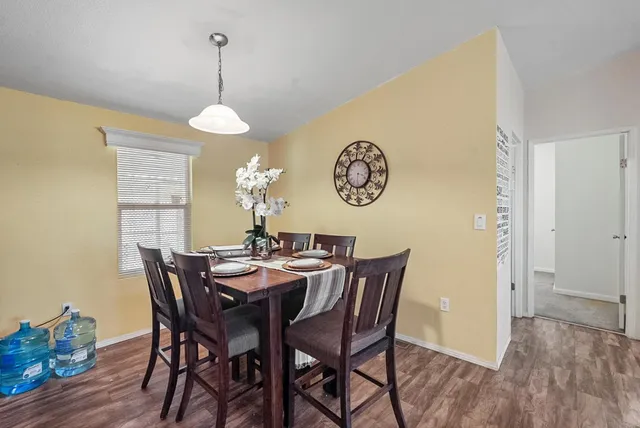 a kitchen with stainless steel appliances granite countertop a stove top oven a sink dishwasher a dining table and chairs with wooden floor