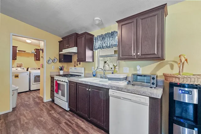 a kitchen with stainless steel appliances granite countertop wooden cabinets a refrigerator a sink a stove a refrigerator and cabinets