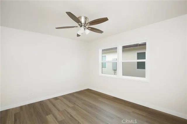 an empty room with wooden floor ceiling fan and windows